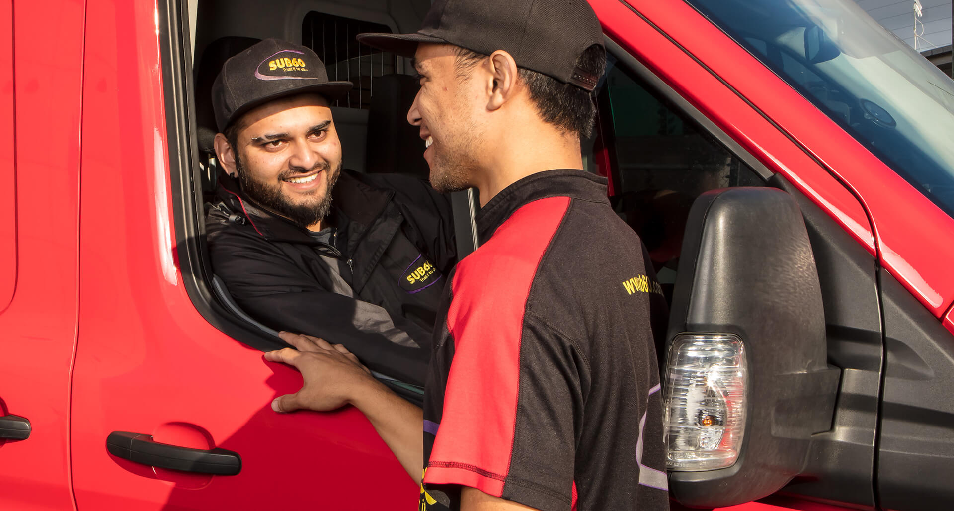 Two courier drivers smiling and chatting about becoming a courier driver.